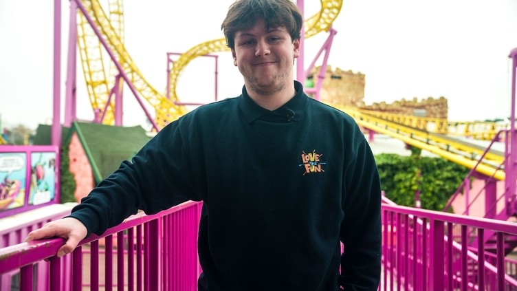 A man poses in front of an outdoor fairground ride