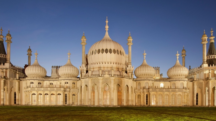 Large palace with white domes and minarets at night