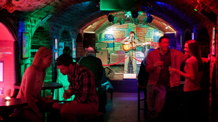 Man on stage playing a guitar in a club with arched ceilings