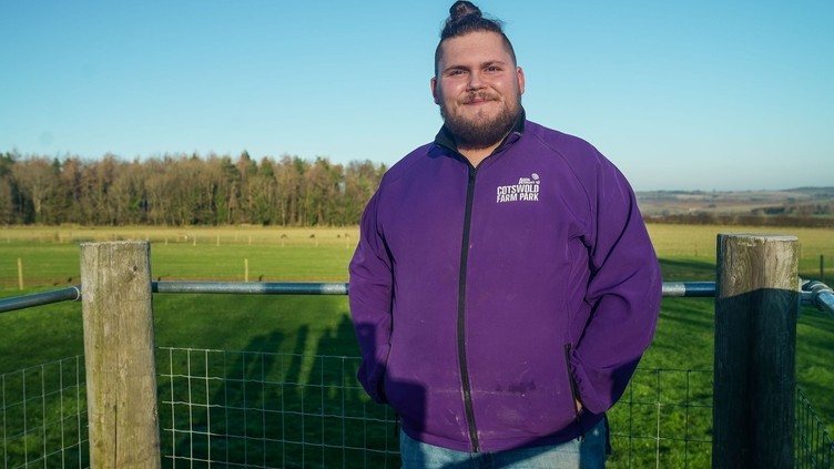 A man poses in front of farmland