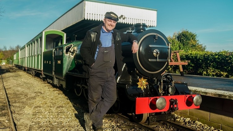 A railway worker poses next to a small railway train