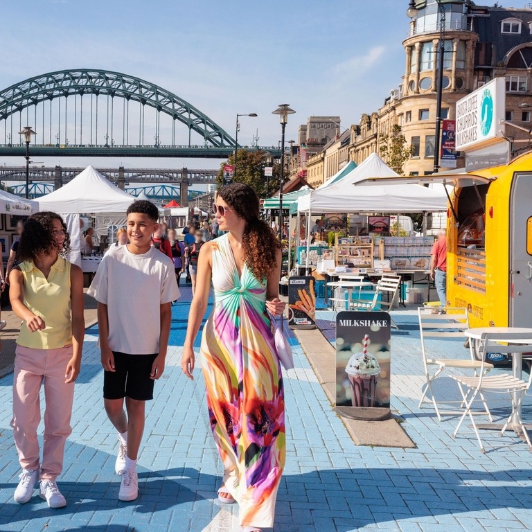 A family visit a Sunday market by the river Tyne in Newcastle upon Tyne
