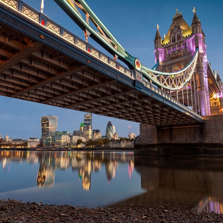 A bridge over a river in a city at dusk