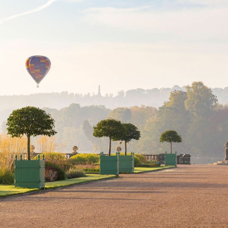 Hot air balloon rises over a lake with the early morning sun