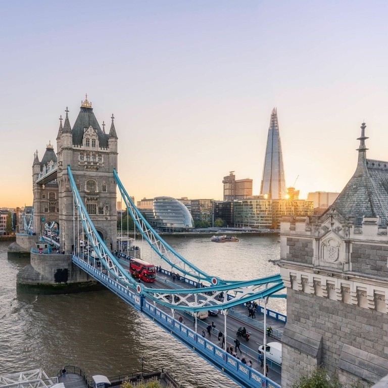 View of Tower Bridge and Shard at sunset, with a red bus going across it