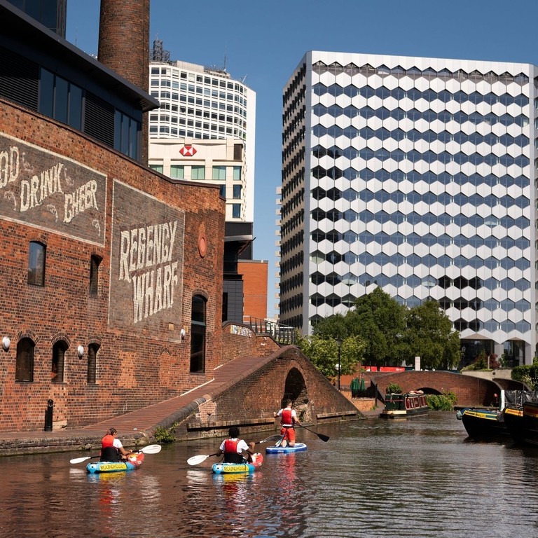 A group of people paddleboarding past the Regency Wharf in Birmingham.