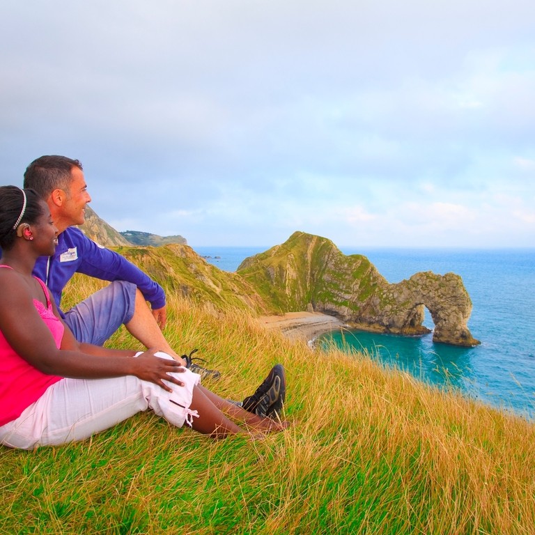 Couple sat on the grass looking out to the sea