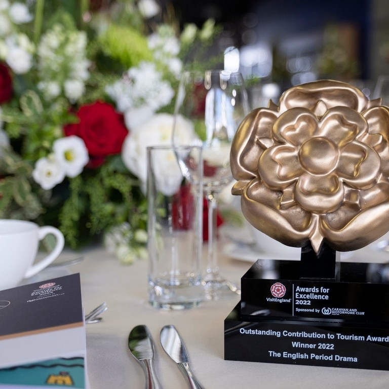 Close-up shot of a trophy on a table with floral centre piece in background