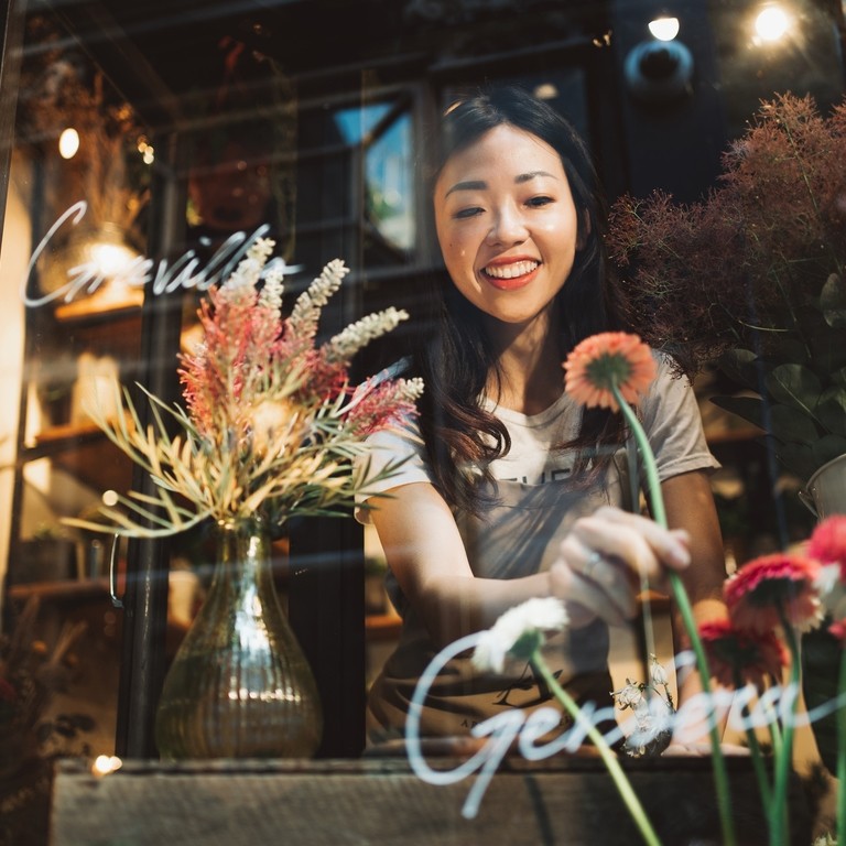 Asian young florist working on the arrangement of flowers for her shop.