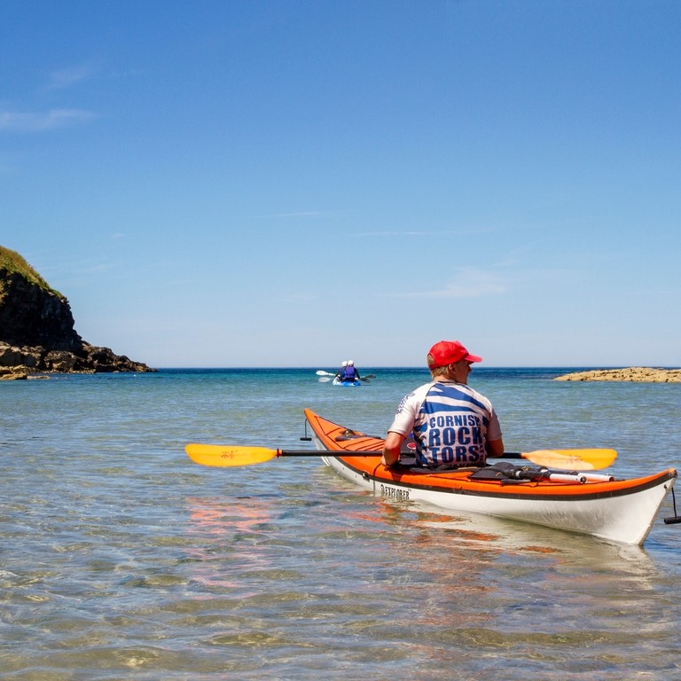 A close up of someone kayaking through the sea off the coast of Cornwall