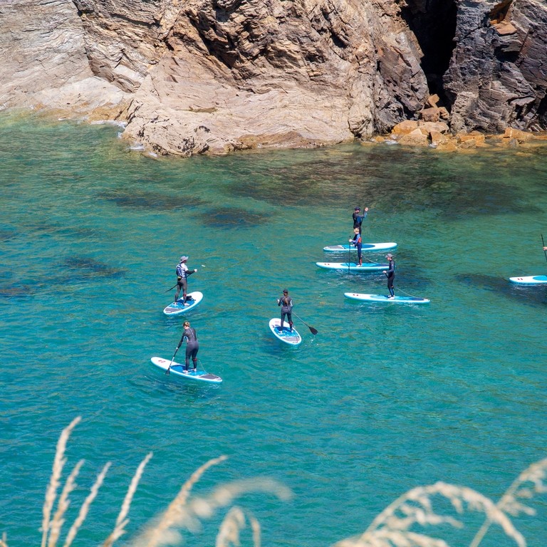 A group of people paddleboarding off the coast of Cornwall