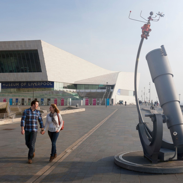 Couple walking hand in hand on the waterfront by a modern building