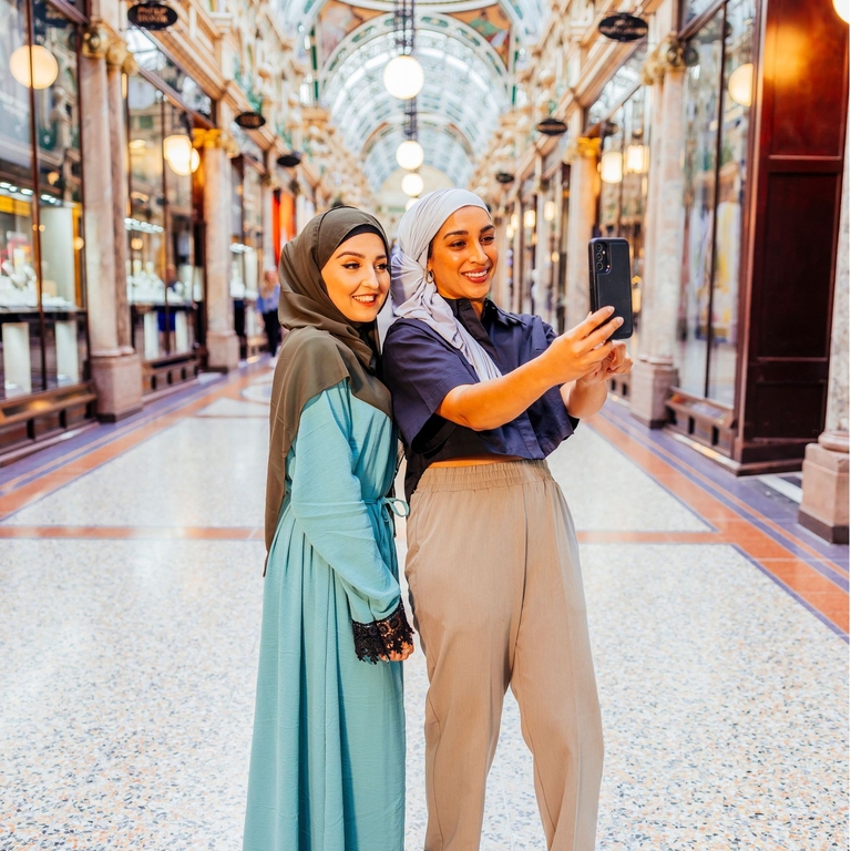 Two women take a picture together in an indoor shopping arcade