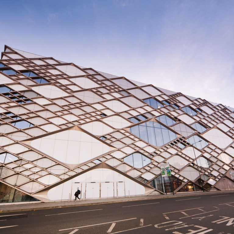 Exterior view of a large modern university building with criss-cross patterns