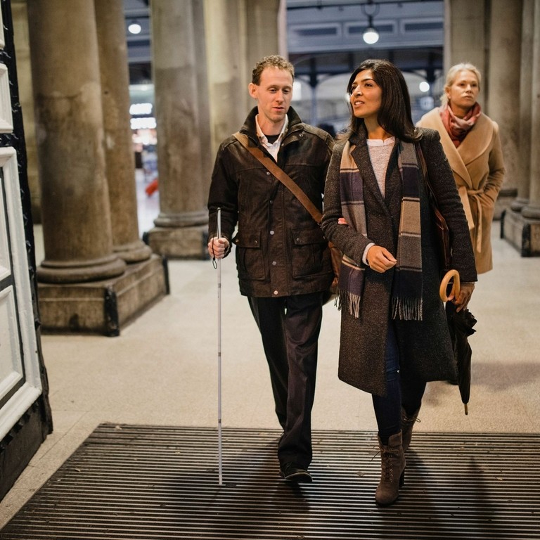 Man and woman walking into train station, Newcastle central station, UK