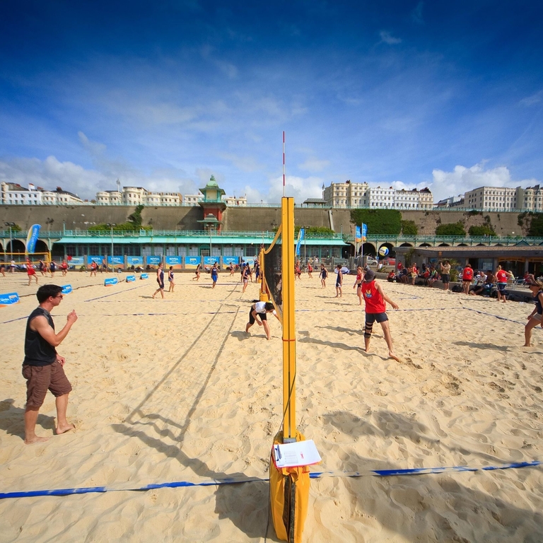 People playing volleyball on a beach in the sunshine
