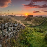 View along long stone wall over the fields at sunset