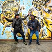 how much do brown tourist signs cost Two men standing in front of street art, dancing