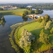 An aerial view of the grounds surrounding Blenheim Palace, an eighteenth-century country house, surrounded by gardens, trees and a lake crossed by a bridge to reach the front of the house. Blenheim Palace - Silver award winner for the Large Visitor Attraction of the Year at the VisitEngland Awards for Excellence 2023.