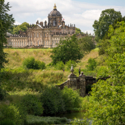 Large country house surrounded by trees with stream in the foreground