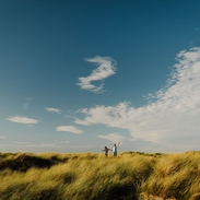 Two young young boys jump in sand dunes at a beach