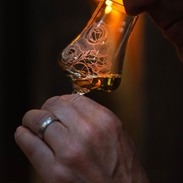 A person smelling whisky in a glass.