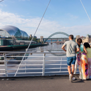 Family standing on a bridge overlooking a city river