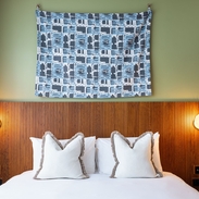 A hotel room bed with crisp white sheets and pillows with a wooden headboard against a green wall