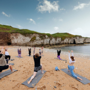 A group of people practising yoga on a beach