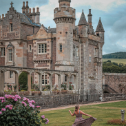 A woman twirling her dress in the gardens of a stately mansion.
