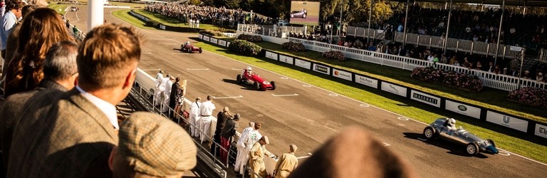 People in a grandstand watching a vintage sports car race
