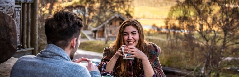 A couple seated, overlooking valley, having a hot drink