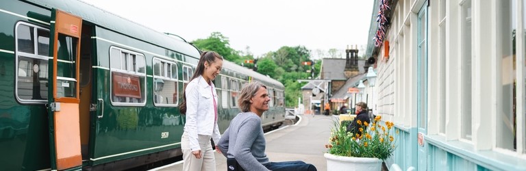 Man using a wheel chair and woman about to go into the ticket office of Grosmont Station