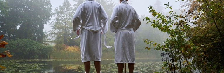 Two men in robes on the swimming platform of a lake in an autumnal setting