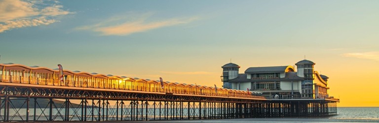 A majestic pier stretching out into the ocean with the tide out at sunset.