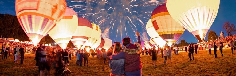 Lit up hot air balloons and fireworks in the night sky