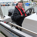 Smiling man with lifejacket steering a wheelyboat