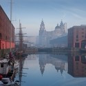 Dock. Waterfront with wooden ship. Tall buildings on skyline