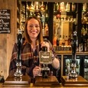 Woman serving drinks behind the bar in a pub