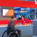 Male wheelchair user at museum talking to female staff member