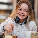 Young female with Downs Syndrome sat at a table laughing