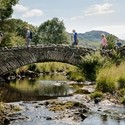 Group of friends out walking in the lakes crossing bridge in the Lake District
