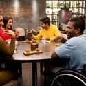 Group of friends, one wheelchair user, sat around a table