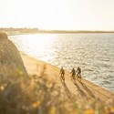 Three cyclists on a coastal path during sunset
