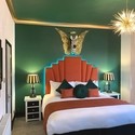 View of a bedroom at The 25 Boutique B&B, Devon with a spiky light fitting and the head of a zebra in the centre of a pair of gold wings hung above the bed. Gold winner of the B&B and Guest House of the Year in the VisitEngland Awards for Excellence 2022