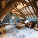 Lounge area at the top of a timber framed building, with exposed ceiling beams, a large leather sofa and wooden coffee table facing a flat-screen TV at Rowley Farm Holidays. Bronze winner of the New Tourism Business of the Year in the VisitEngland Awards for Excellence 2022