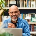 Cheerful handsome mature man at home speaking on video call using laptop