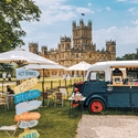 A food truck, parasols and direction signs in the ground of a castle