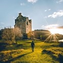 Man walking towards a castle with sun rising in the sky